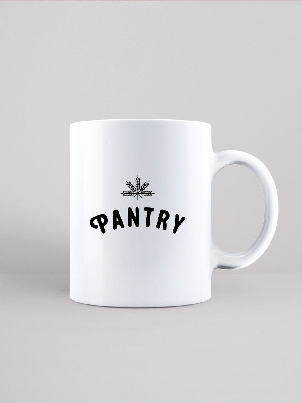 White ceramic mug that is speckled with black. Pantry logo and leaf printed in black.